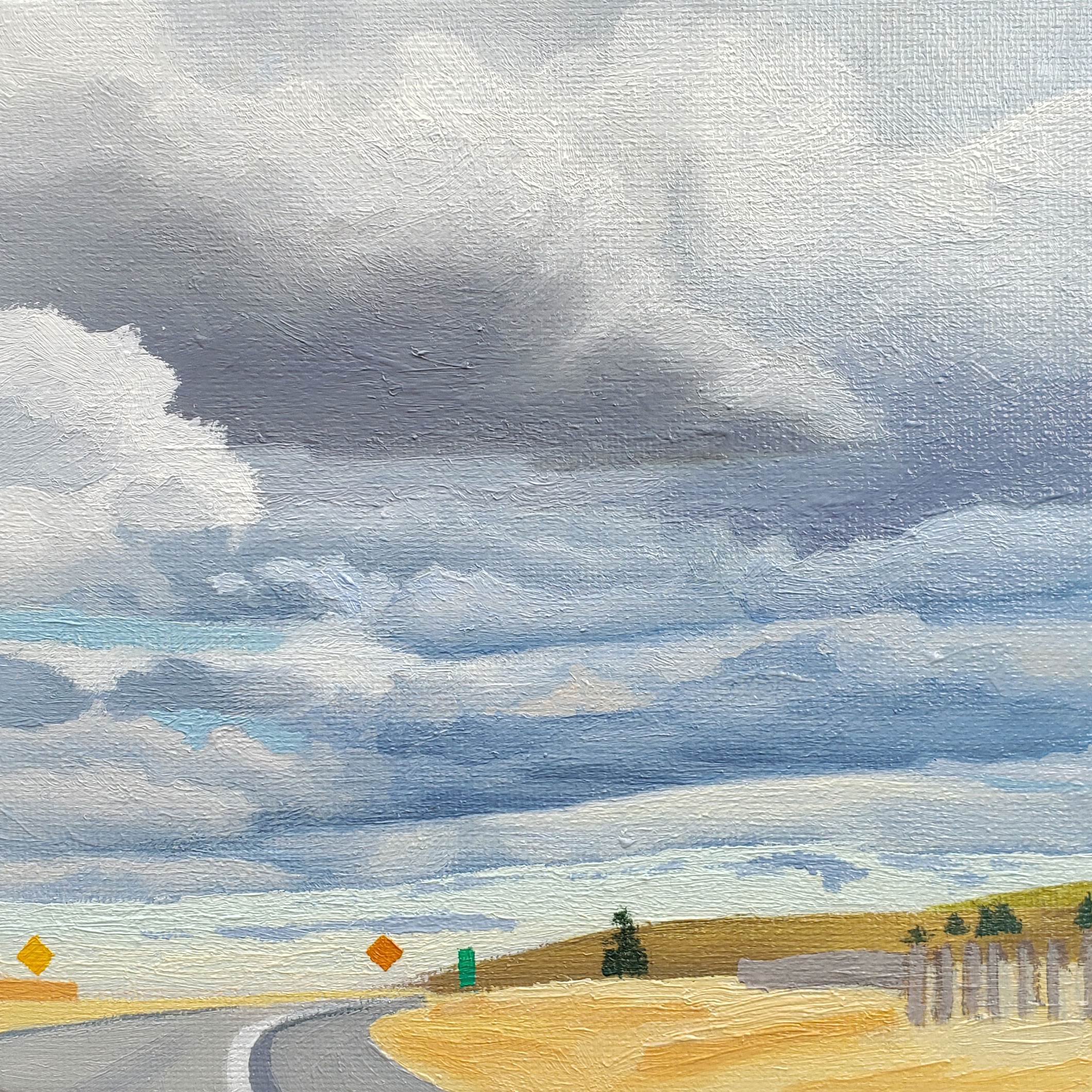 heavy blue and grey clouds over a curving freeway with road signs
