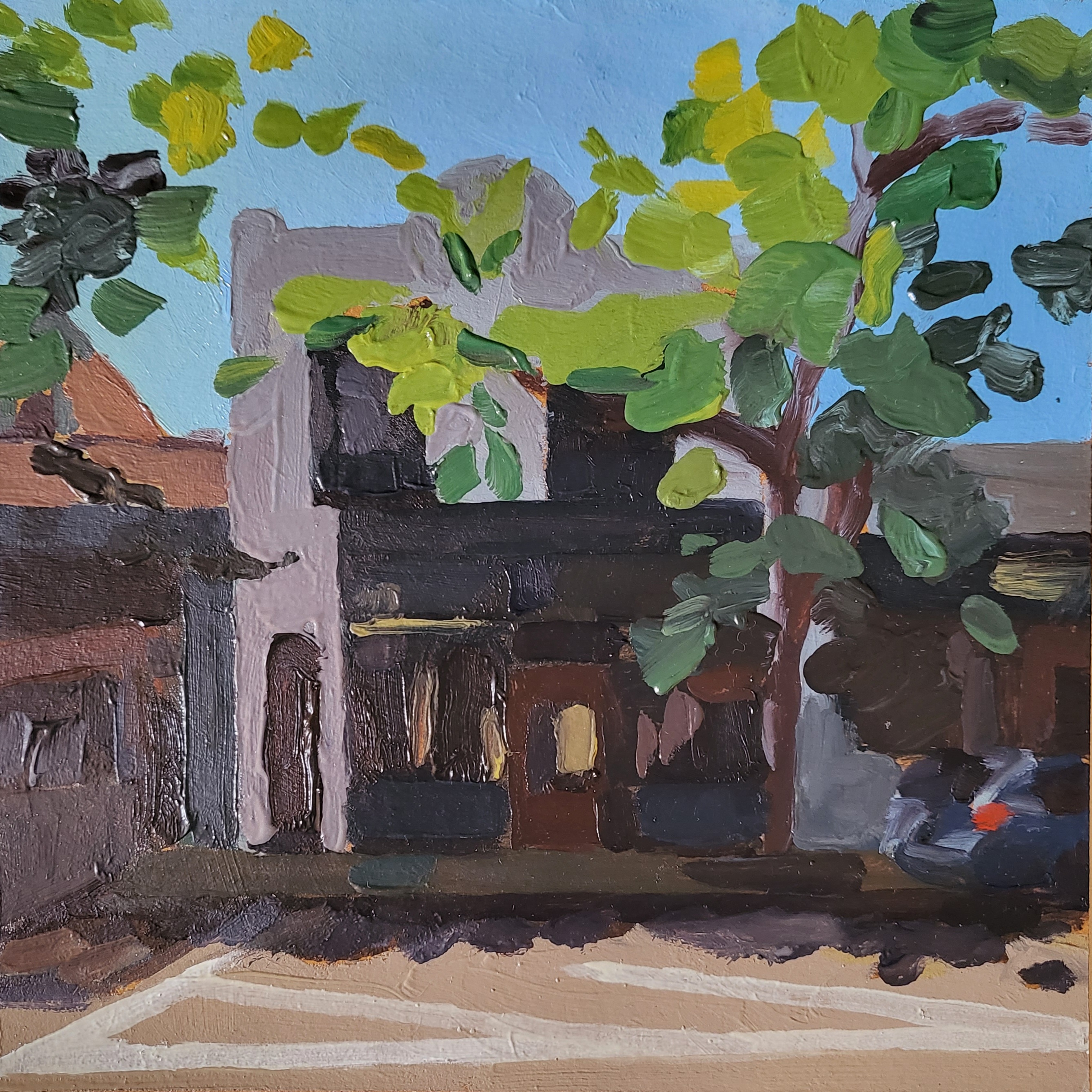green leafy tree in front of old bar storefront